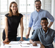 3 people smiling whilst at their desk