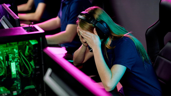 An esports player holding her head in her hands