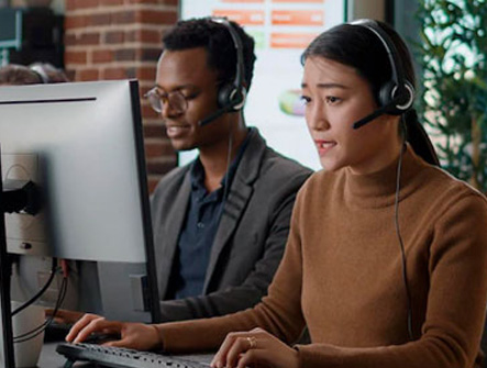 A man and woman talking with a headset on at work